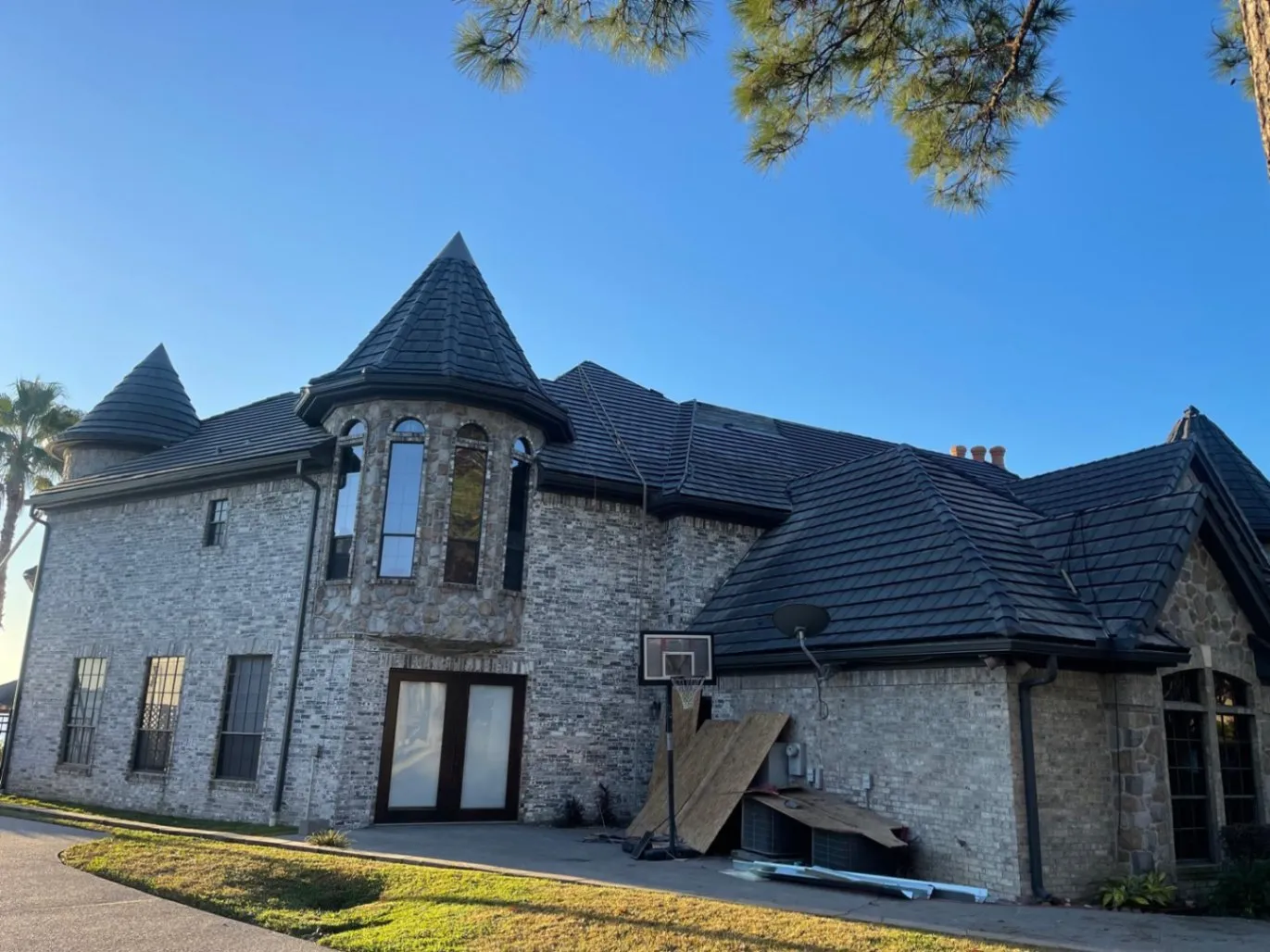 Stone and brick estate home with dark tile roof and turret