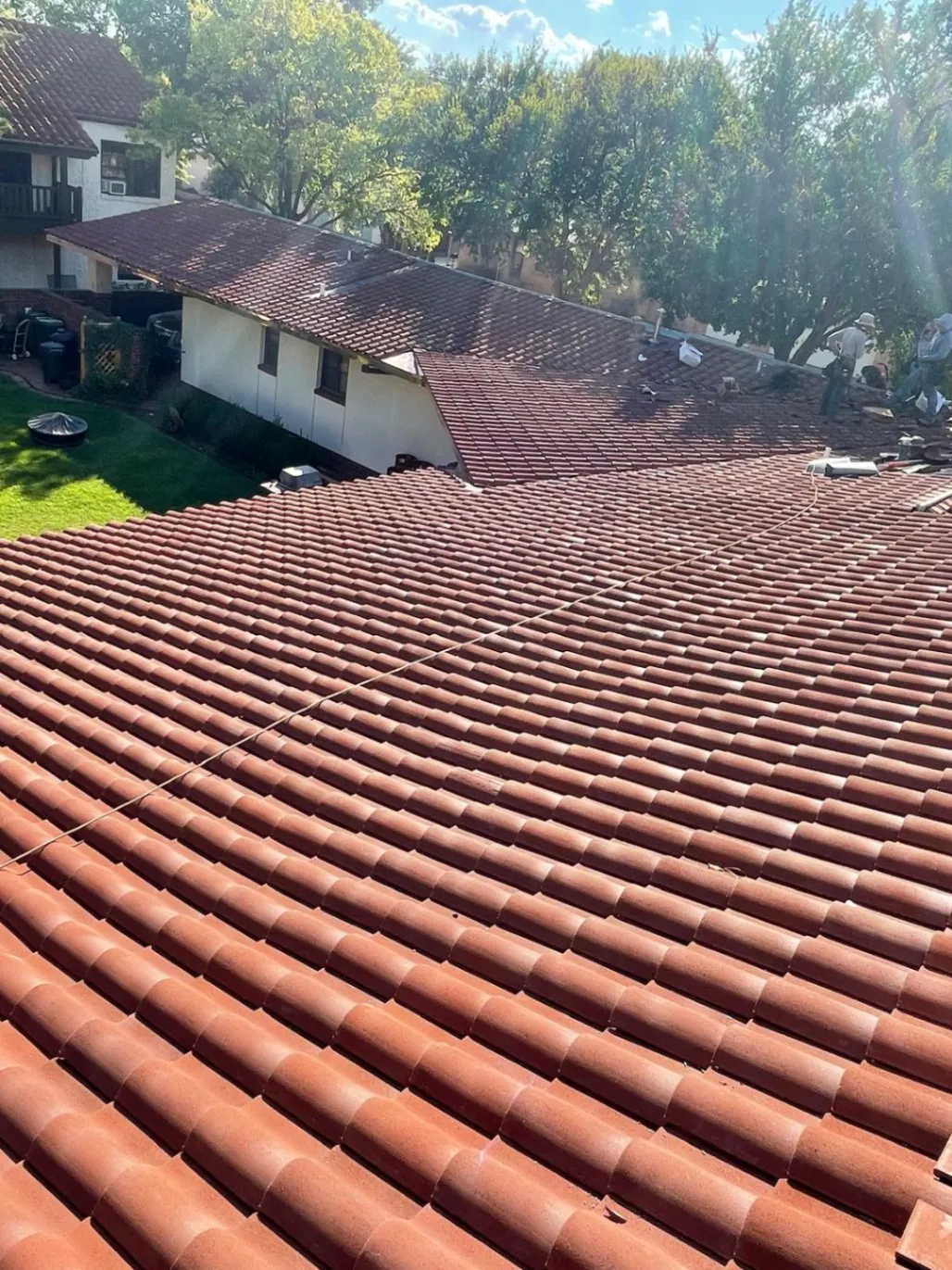 Crew installing red clay tile roofing